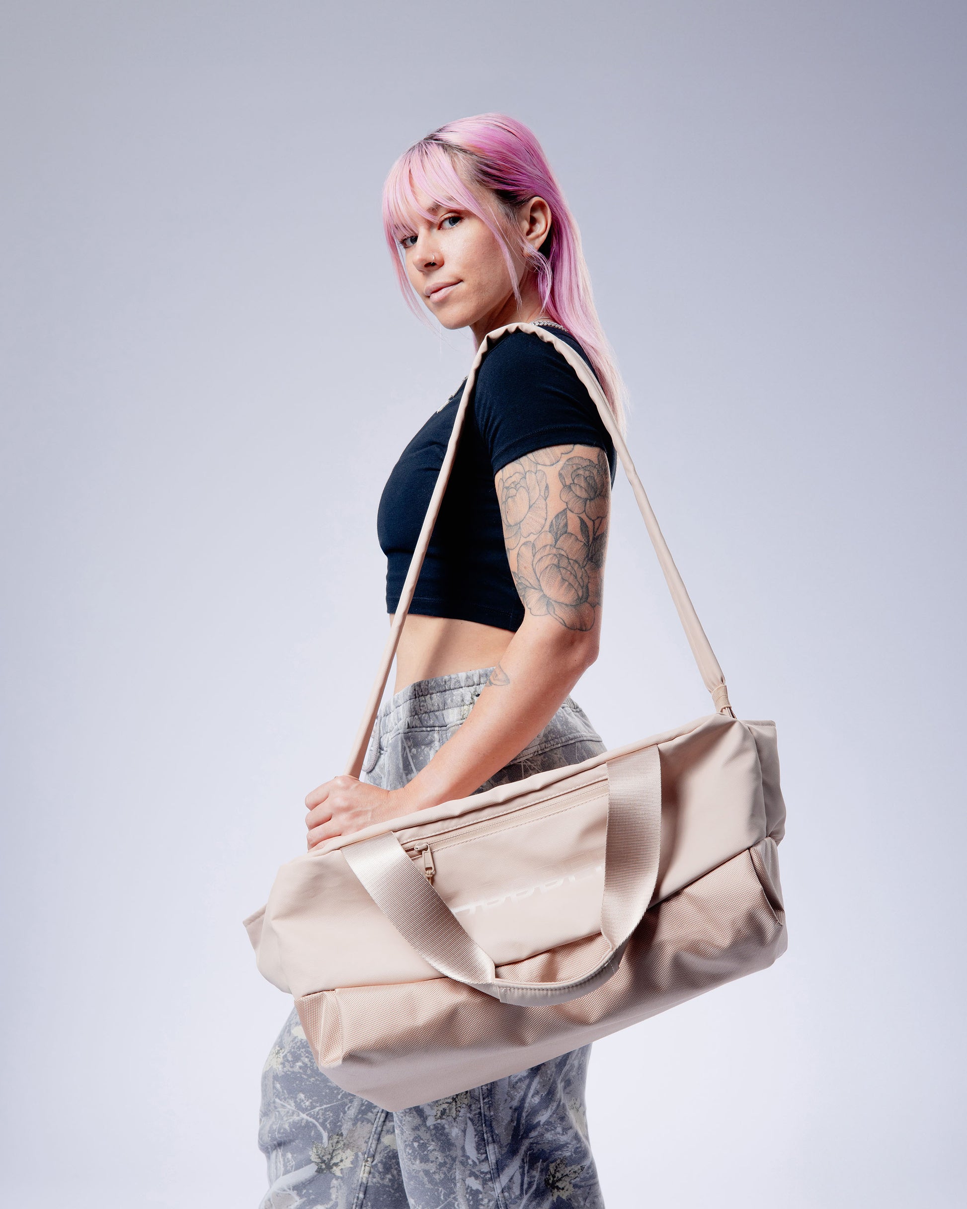 person carrying a beige uppper gym bag on a plain background